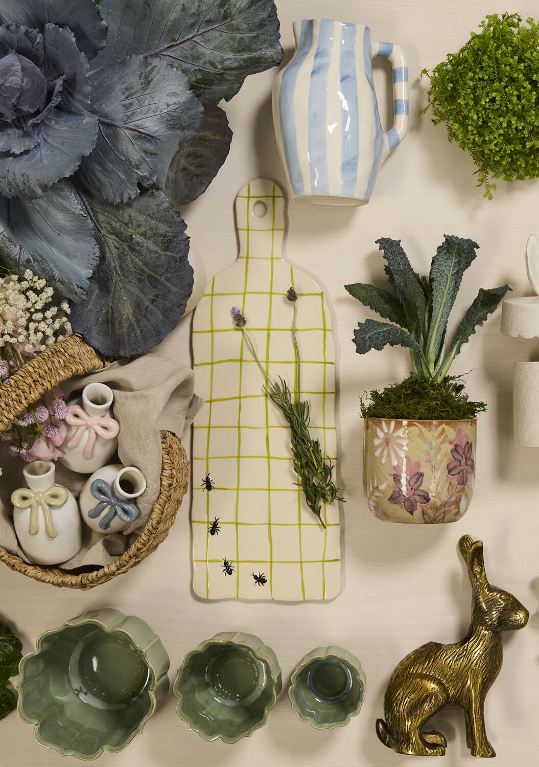 Collection of decorative items including plants, vases, and a cutting board on a white surface.