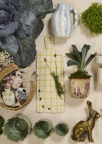 Collection of decorative items including plants, vases, and a cutting board on a white surface.