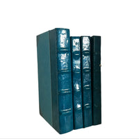 A set of teal blue patent leather bound books with hardback covers.