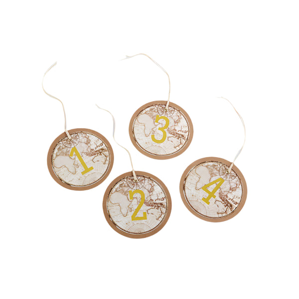 Four round kraft cardstock table numbers with a vintage-inspired map design and gold foil numbers, placed on a white surface.