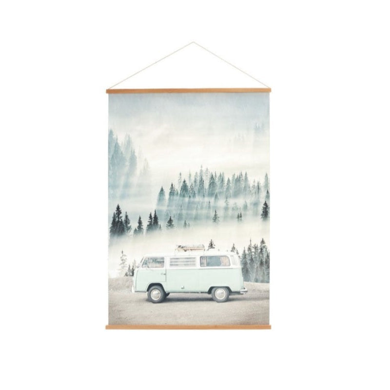 A canvas banner featuring a vintage design of a Volkswagen bus with a forest and mountain background, mounted in a simple wooden frame.