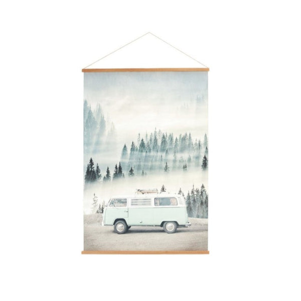 A canvas banner featuring a vintage design of a Volkswagen bus with a forest and mountain background, mounted in a simple wooden frame.