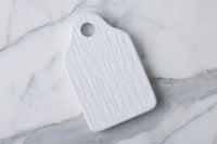 White cheese board with a handle on a marble surface