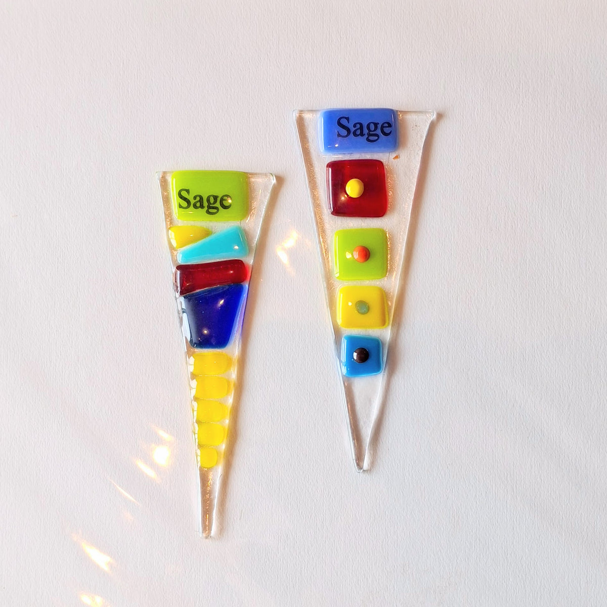 Two colorful glass pieces with 'Sage' text on a white background