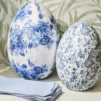 Two decorative eggs with blue floral patterns on a neutral background