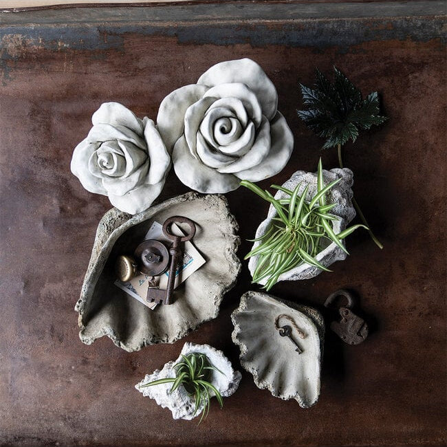 Decorative arrangement with concrete flowers, shells, and keys on a wooden surface
