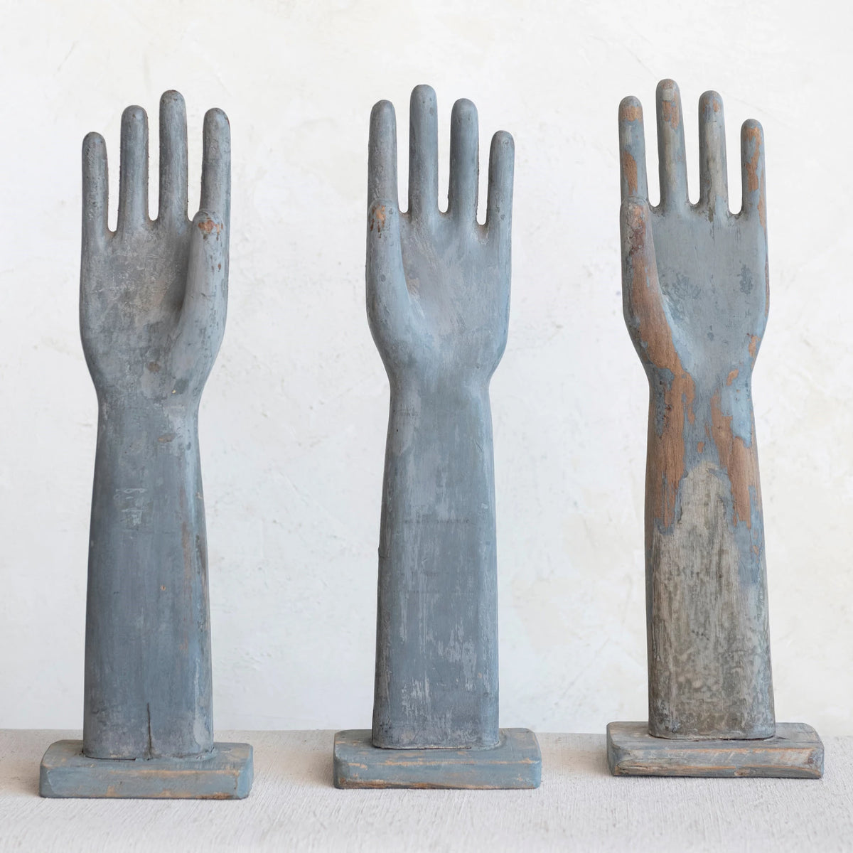Three rustic wooden hand-shaped figures on a white background