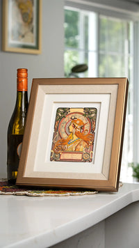 Framed quilled card on a surface with a bottle of wine in the background
