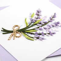 Quilled greeting card featuring lavender flowers and a bow on a white background