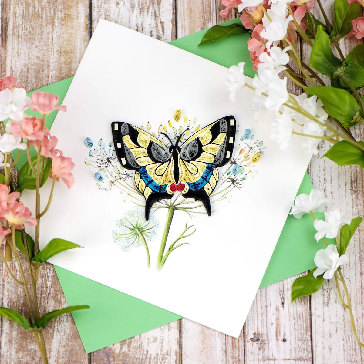 Quilled butterfly greeting card with flowers on a wooden background