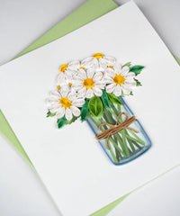 Greeting card with a quilled design of a jar of daisies on a white background