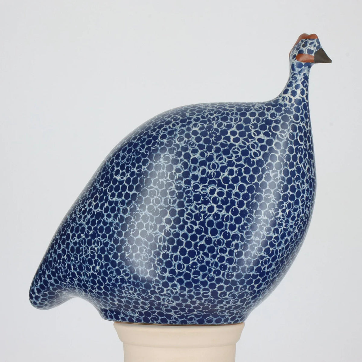 Ceramic guinea fowl figurine with blue and white pattern on a gray background