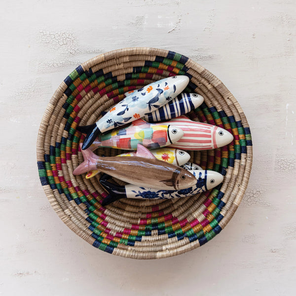Colorful fish-shaped figurines in a woven basket on a light background