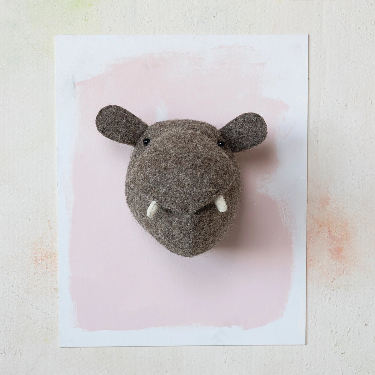 Hippo-shaped decorative head on a pink and white background
