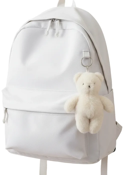 White backpack with a teddy bear keychain on a white background