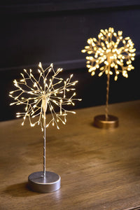 Two decorative LED light sculptures meant to mimic the look of a dandelion on a wooden surface with a dark background