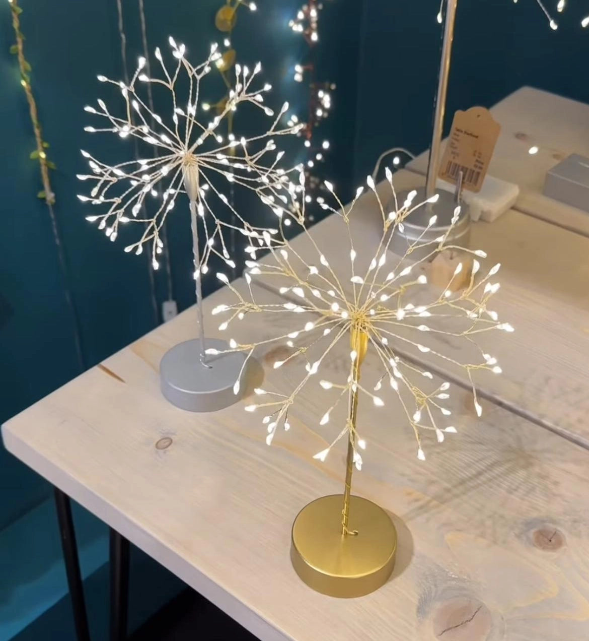 Decorative LED lights in a dandelion shape on a wooden table with a blue wall background