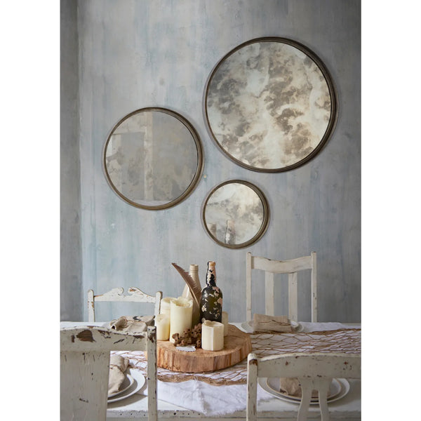 Dining room with round mirrors on the wall and a table set for a meal.