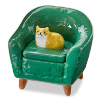 Green ceramic chair with an orange cat figurine on a white background