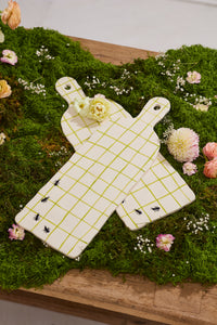 Two white ceramic cutting boards with green grid lines on a bed of green moss and flowers.