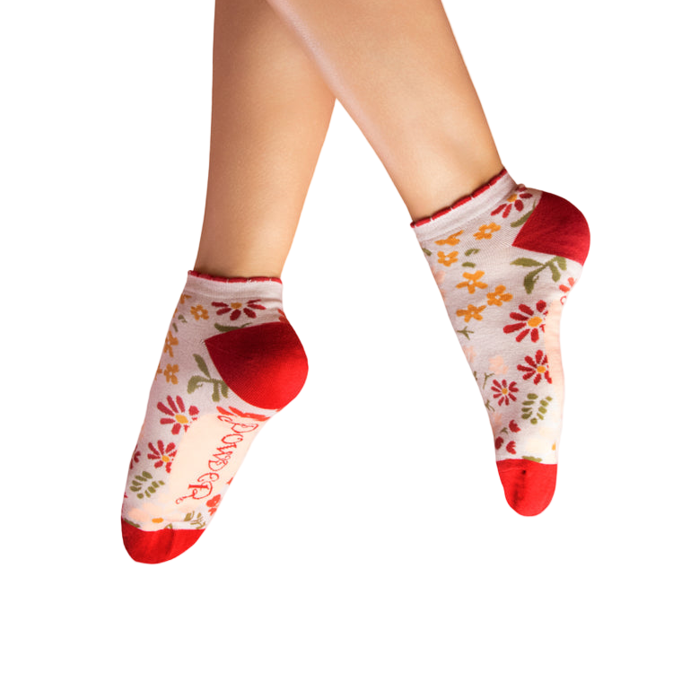 Floral-patterned socks with red toes and cuffs worn by a person on a white background