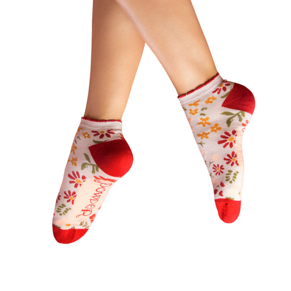 Floral-patterned socks with red toes and cuffs worn by a person on a white background