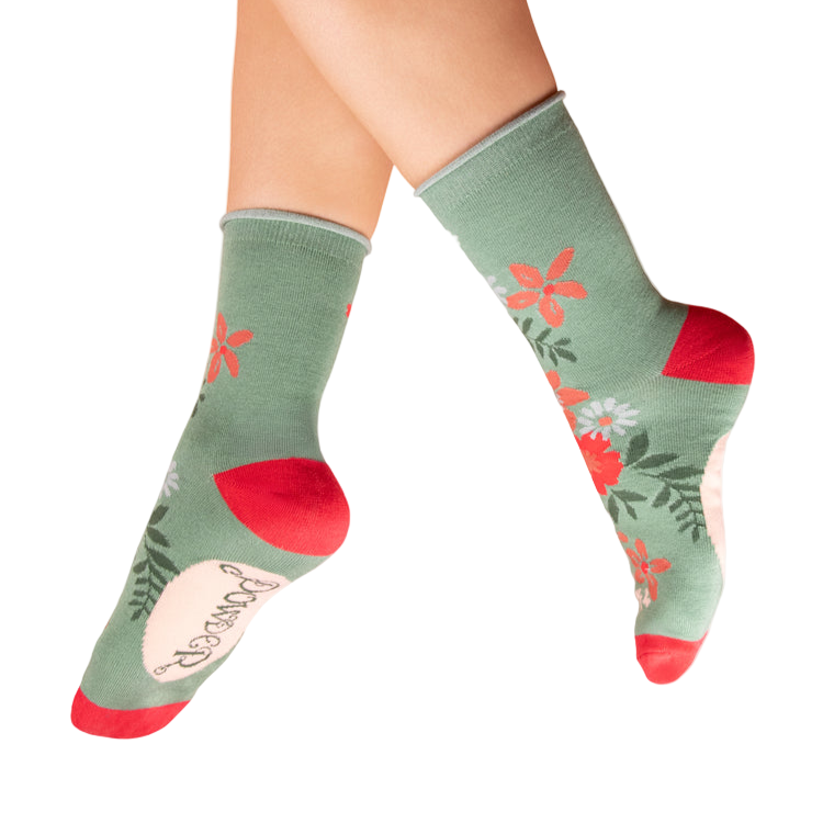 Green socks with floral patterns and red accents worn by a person on a white background