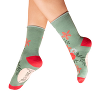 Green socks with floral patterns and red accents worn by a person on a white background