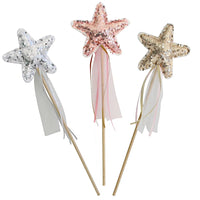 Three star-shaped sequin wand toppers on wooden sticks, shown against a plain white background. The left wand is silver, the center wand is rose gold, and the right wand is champagne gold, each with long sheer ribbons hanging below the stars.