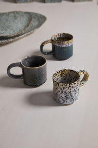 Three ceramic mugs with unique patterns on a light surface